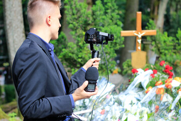 The professional man transmitting the funeral live. Funeral recording. Cameraman at the cemetery recording the burial. Funerals online. Funerals live.