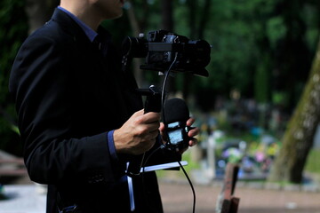 The professional man transmitting the funeral live. Funeral recording. Cameraman at the cemetery recording the burial. Funerals online. Funerals live.