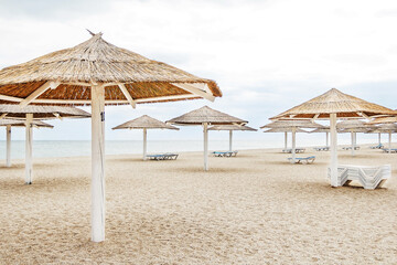 Beautiful beach on the seashore. Lots of sun umbrellas. Sun loungers on the beach. Beach chairs and large umbrellas. Clean beach without people. Summer vacation at the sea.