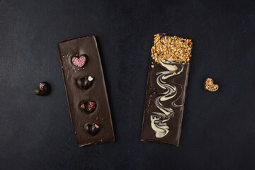 Dark chocolate bars with decorations isolated on a dark background. Top view, flat lay.