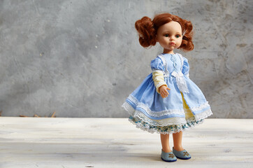 doll in a yellow and blue dress, on a gray concrete background. copy space