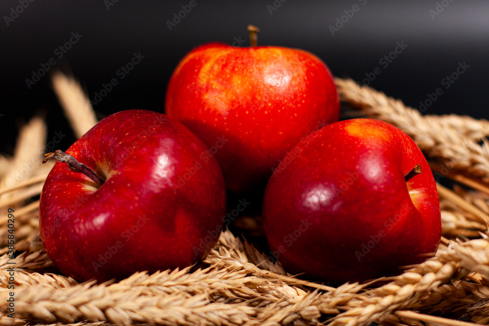 Wall mural three red apples lie on a bunch of ripe wheat ears.