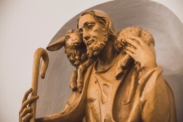 Carved wood statue of Jesus with a lamb on his shoulders in the Church
