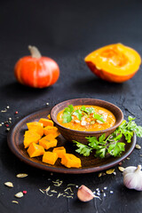 Delicious healthy pumpkin soup, herbs, and ingredients for the dish. Creative atmospheric decoration