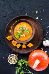 Delicious healthy pumpkin soup, herbs, and ingredients for the dish. Creative atmospheric decoration