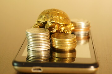 Metal turtle with coins on your mobile phone. Earning money online.