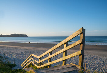 Steps and railing down to wide sandy Onetangi Bay beach on Waiheke Island New Zealand.