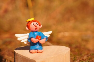 Figure of an angel made of plasticine on a colored background.