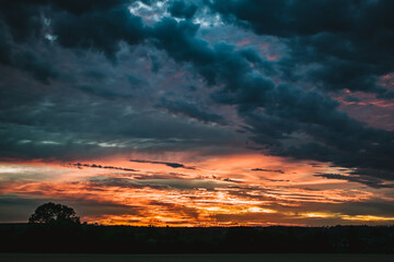 Beautiful wide angle view for dramatic sunset sky with clouds, astonishing sun set in bright colors on British agricultural grounds, most amazing view in UK, high contrast and saturation photography