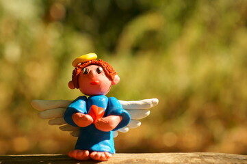 Figure of an angel made of plasticine on a colored background.