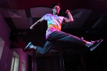 Professional break dancer in motion, practicing modern hip-hop dance in pink neon light