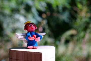 Figure of an angel made of plasticine on a colored background.