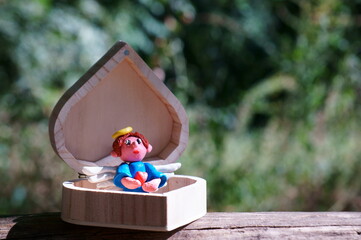 Figure of an angel made of plasticine on a colored background.