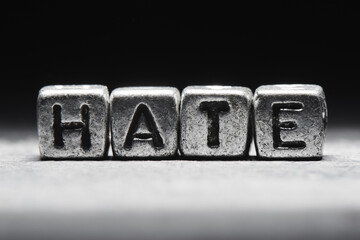 Hate concept. 3d inscription on metal cubes on a gray black background isolated in grunge style