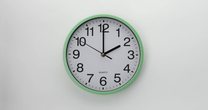 Quartz wall clock on a white background. The clock shows two o'clock. 4K DCI video. 