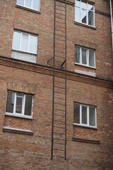 A fire escape on a brick building with white modern windows.