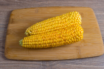Corn lies on canvas. Fresh corn closeup. Corn cob on a plate. Sweet corn on background for food ingredients and cooking concept.