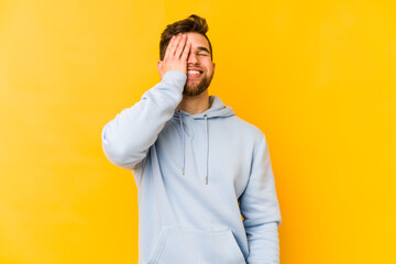 Young caucasian man isolated on yellow background laughing happy, carefree, natural emotion.