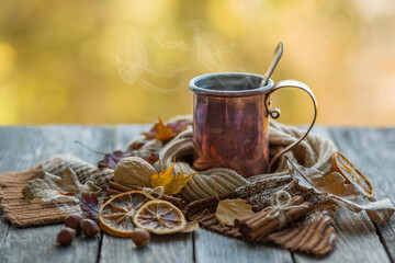 Obraz na płótnie Canvas Copper mug with hot tea on a wooden table with autumn leaves. Retro style photo