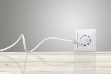 White electrical plug in the electric socket on a wall