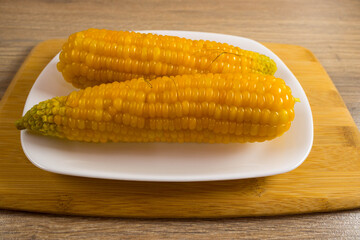 Corn lies on canvas. Fresh corn closeup. Corn cob on a plate. Sweet corn on background for food ingredients and cooking concept.