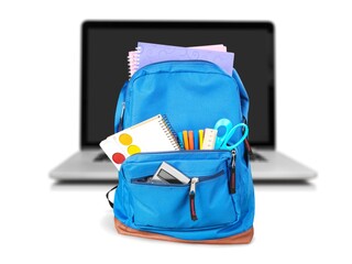 Colorful school supplies in backpack on laptop background