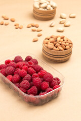 Raspberries in plastic container. Almonds in wooden box.