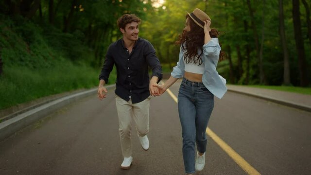 Energetic couple moving fast on road in park. Man and woman having fun outdoors