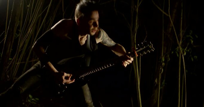Rock artist heavy brutal guitar playing in the dark in flashing light. a man plays an electric guitar. Music video of a punk, heavy metal or rock band