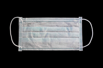 Close-up of medical or surgical white green color mask for protection against viruses and bacteria, isolated on black background. The concept of medical supplies or accessories for personal protection