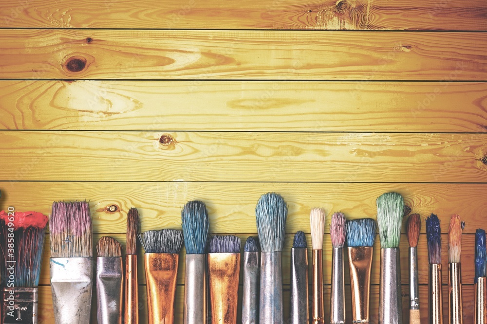 Wall mural row of artist paint brushes on wooden desk