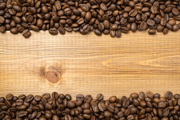 Frame of scattered coffee beans on wood background with copy space.