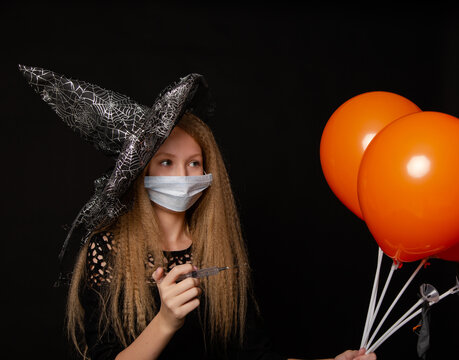 Cute girl teen in a mask from COVID19 on a black background with balloons on Helluin