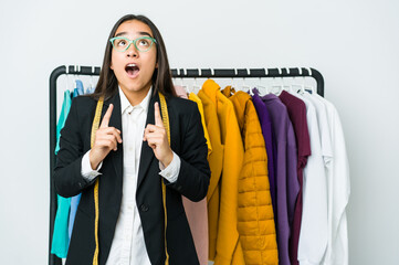 Young asian designer woman isolated on white background pointing upside with opened mouth.