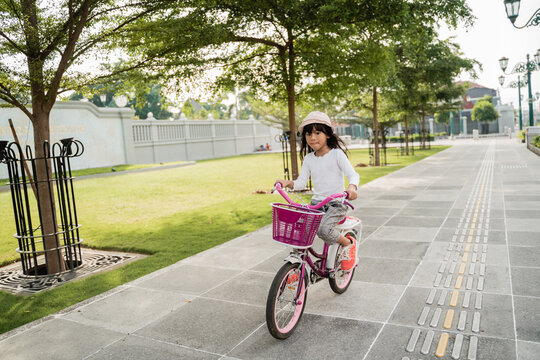 a portrait of a cheerful and happy little girl playing a bicycle in the park when the weather is fine