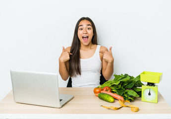 Young dietician asian woman isolated on white background surprised pointing with finger, smiling broadly.