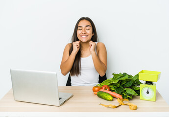 Young dietician asian woman isolated on white background raising fist, feeling happy and successful. Victory concept.