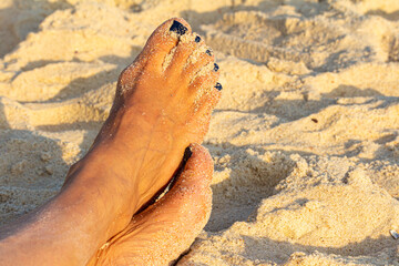 Fototapeta na wymiar pés cruzados de mulher na areia dourada da praia 