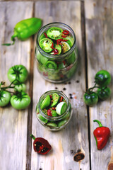 Green tomatoes in jars on a wooden surface. Fermentation of green tomatoes. Country style. Selective focus. Macro.