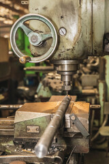 old drilling machine drills a workpiece at the factory