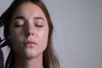 the process of applying makeup to a beautiful brunette by a master in black gloves. beauty, modeling and cosmetics concept.