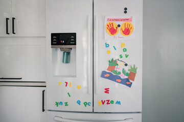 Child art and magnets on white fridge