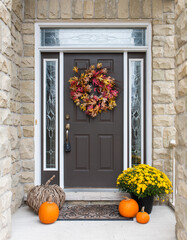 Front door of home decorated for fall with flowers and pumpkins.