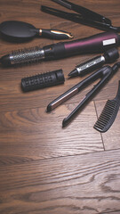 Hairdressing tools on a wooden background. Combs and hair dryer, hair straightener. Long hair...