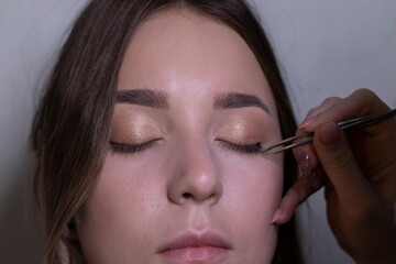 the process of applying makeup to a beautiful brunette. beauty, modeling and cosmetics concept. 