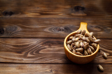 Pistachios in a wooden Cup on a wooden background. Space for text