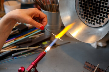The artist heats the glass with a gas burner. The process of making glass jewelry. Master's hands...