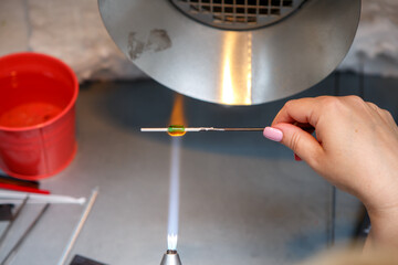 The artist heats the glass with a gas burner. The process of making glass jewelry. Master's hands close up