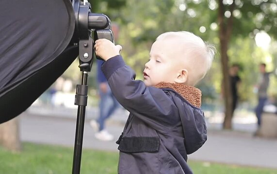cute little boy sets up a flash for the camera and claps his hands