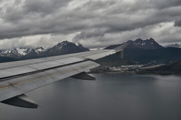 Fototapeta na wymiar Evening Aerial View of Ushuaia Argentina and Surrounding Mountains and Bay Below Airplane Wing